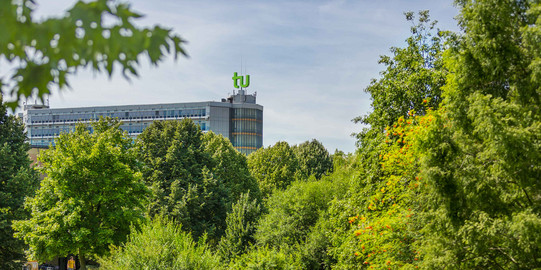TU Dortmund im Sommer_01 Das Mathematikgebäude mit grünen Bäumen im Vordergrund.