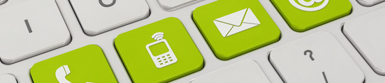 A white keyboard with four green keys. On the green keys are symbols like a telephone, a cell phone, an envelope and an „@“